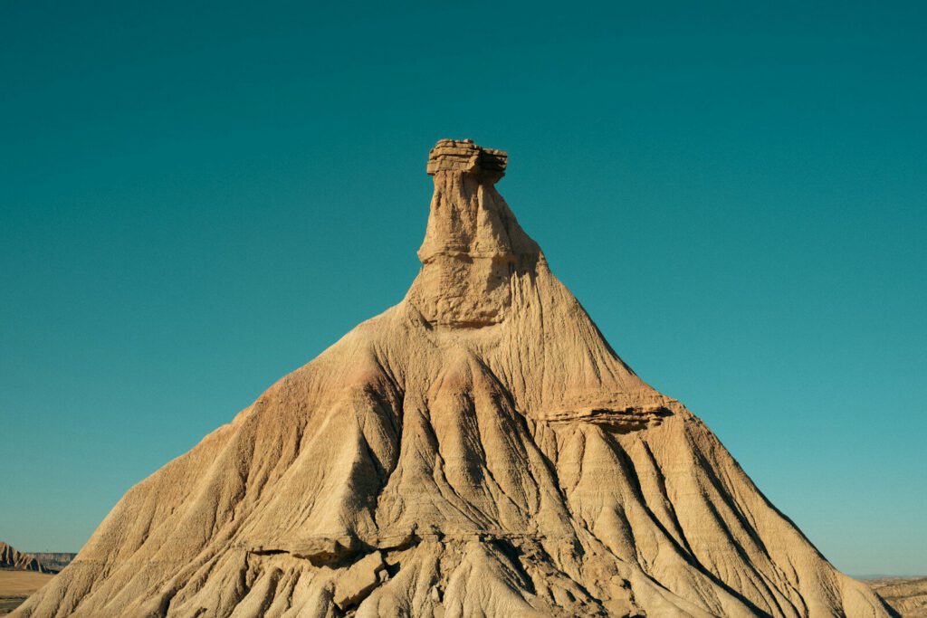 A tall sandstone rock formation with a flat top against a clear blue sky